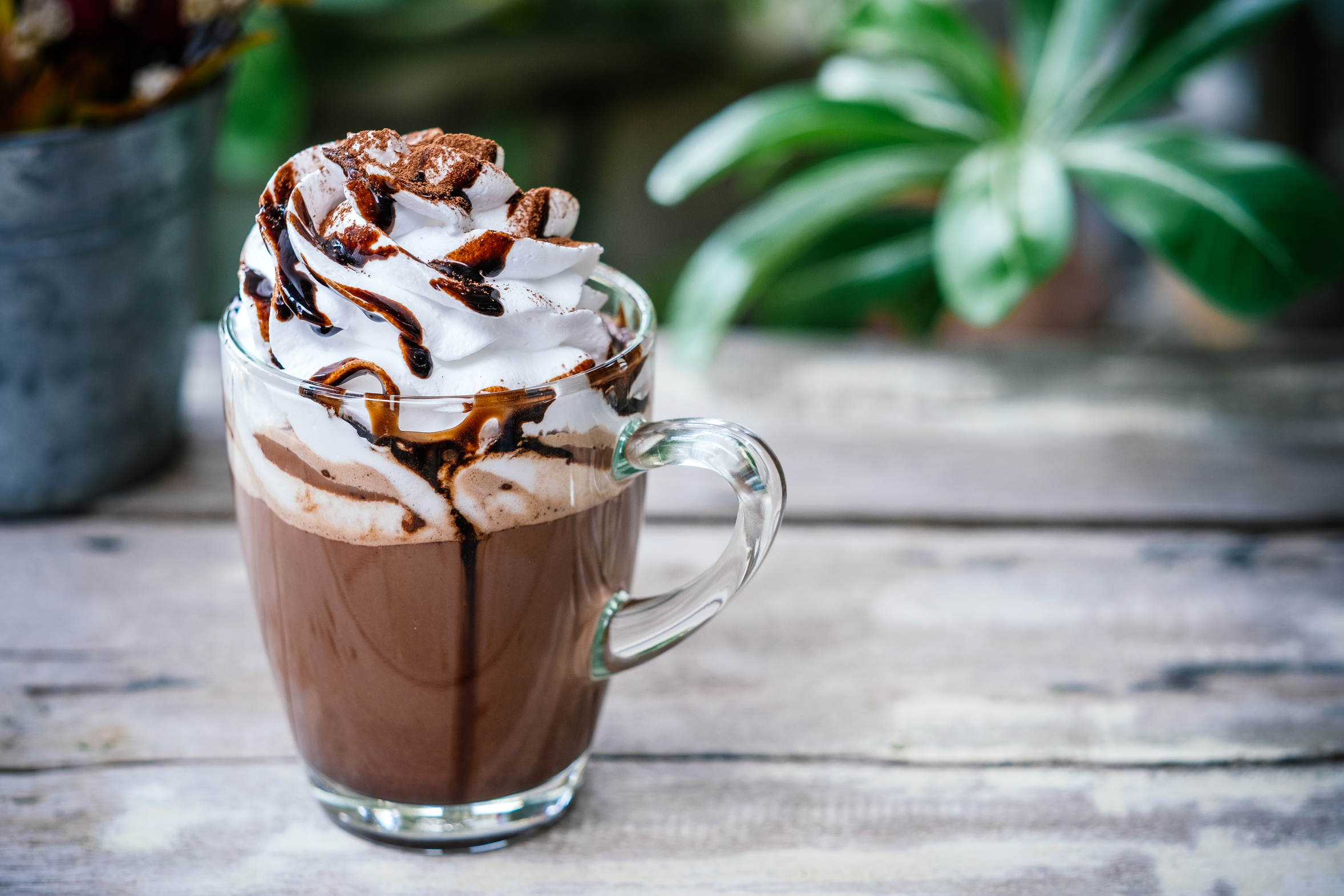 Chocolate quente cremoso servido com chantilly, calda de chocolate e cacau polvilhado